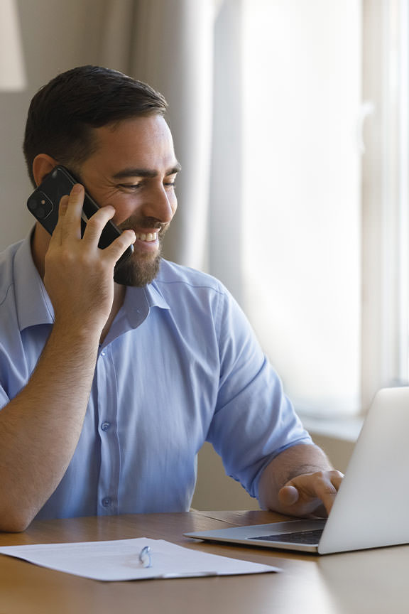 Customer Support Sustainability Alight Lantern Blinds Customer support representative on the phone at a desk with a laptop, representing Alight Lantern Blinds' commitment to sustainability and lasting client relationships