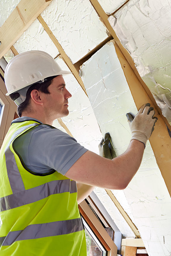 Worker Installing Roof Insulation for Energy Efficiency Worker installing roof insulation to improve energy efficiency in a home